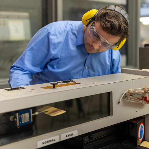 Wearing earmuffs and safety glasses, Rutgers-New Brunswick senior Doug Doyle operates and miniature wind tunnel in a School of Engineering lab on Busch campus.